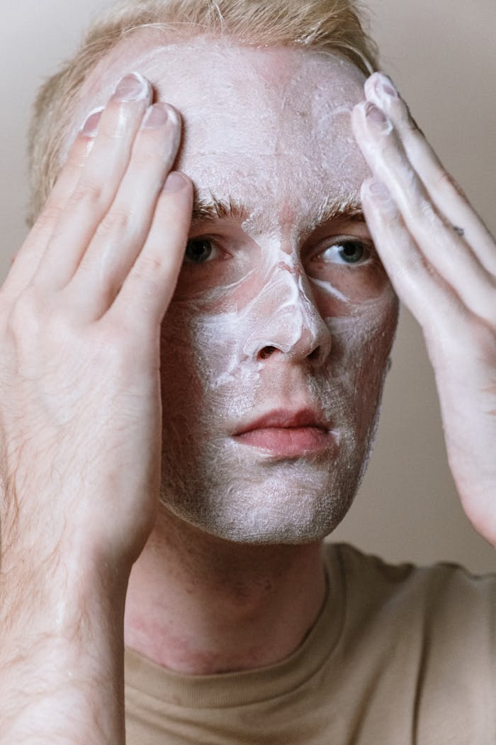 A close-up of a man applying facial cleanser for a skincare routine.