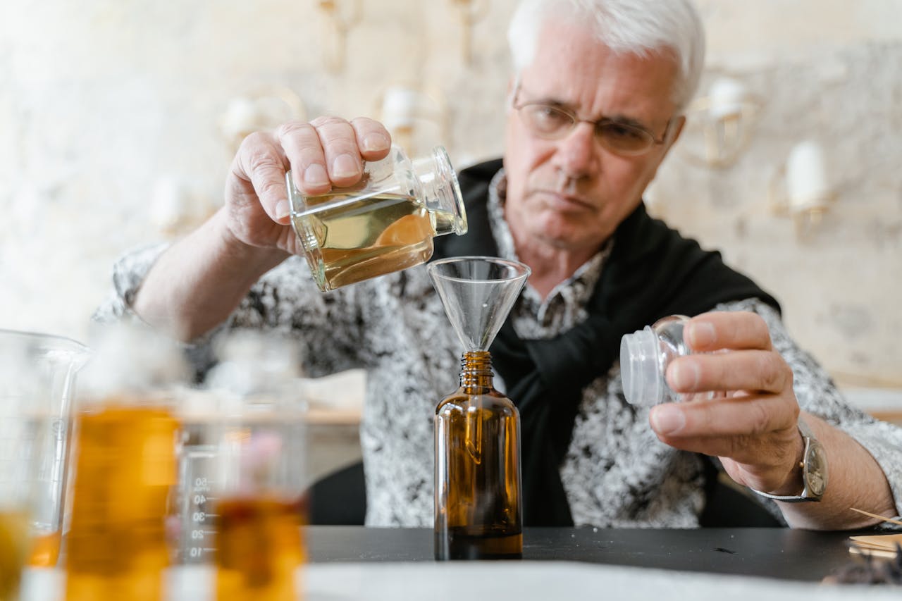 Elderly man carefully blending essential oils indoors for aromatherapy.